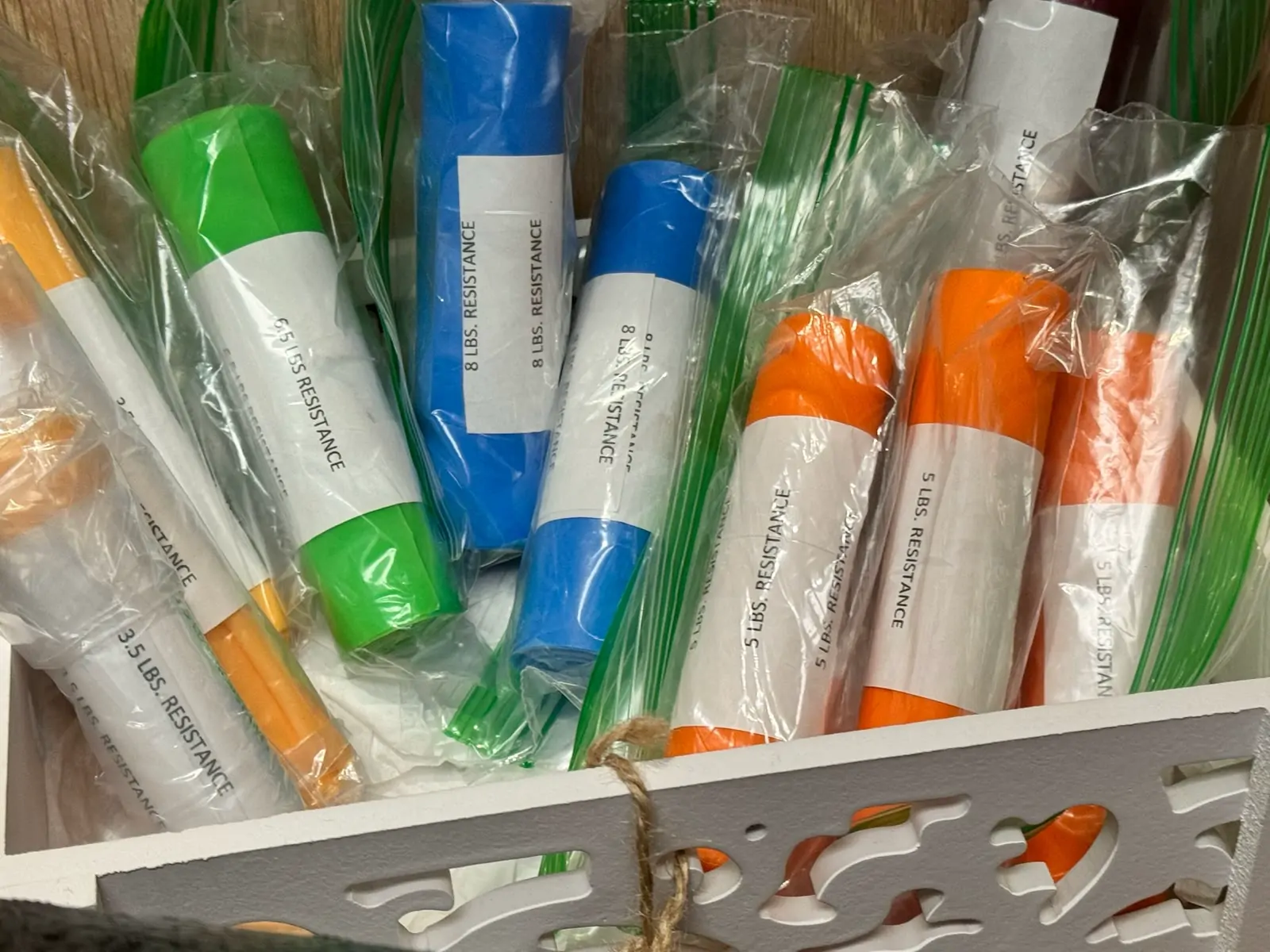 A bundle of new resistance bands in green, blue, orange and yellow, still wrapped.