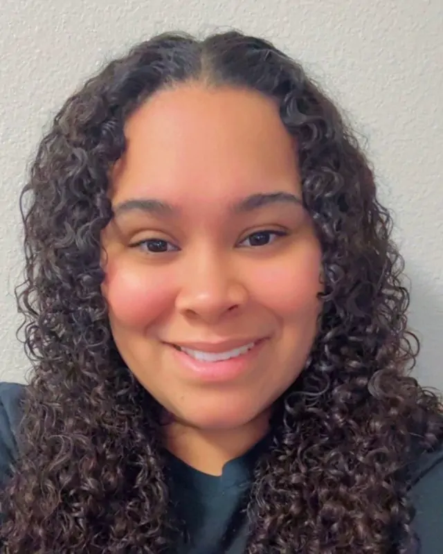 Elisa Canales, receptionist at Direct PT of Huntsville, smiling in a dark top.